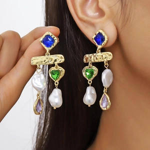 Macro detail of asymmetric baroque pearl drop earrings with multi-colored gemstones