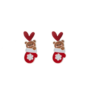 Detail of Christmas earrings featuring red heart, cute brown bear, and snowflake glove charms