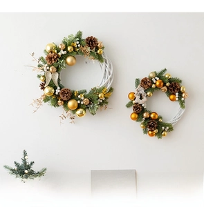 Detail of two white rattan Christmas wreaths with pine cones and golden ornaments