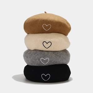 Stack of wool berets with heart embroidery in brown, beige, grey, and black colors