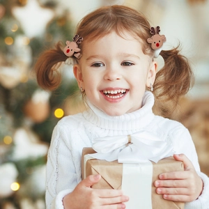 Little girl wearing brown reindeer hair clips in a cozy Christmas holiday setting