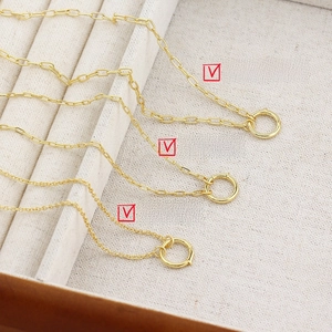 Detailed view of three gold cross and flat chains on a white velvet jewelry tray