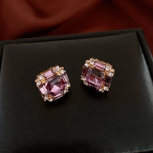 Macro detail of vintage square gold stud earrings with purple crystal and rhinestones