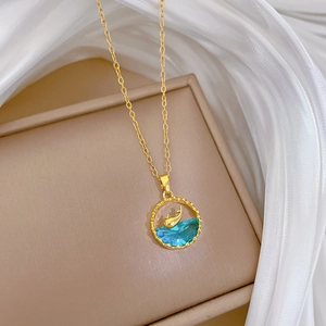 Macro view of gold whale pendant with blue crystal on soft white silk background