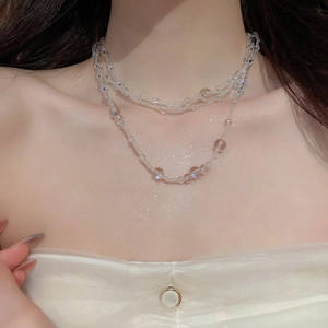 Detailed view of multilayer transparent beaded necklace on female neck with shimmering effect