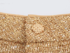 Detailed macro shot of gold tweed fabric with sequins and an intricate braided button