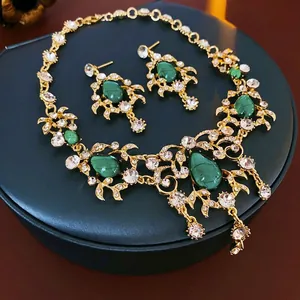 Vintage gold necklace and earrings set featuring green teardrop gemstones and leaf details
