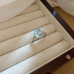 Detail of a crescent moon ring with pearls and crystals in a wooden jewelry box