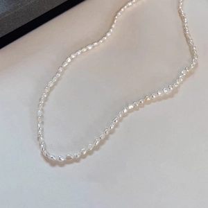 S-shaped natural freshwater baroque pearl beaded necklace on beige background