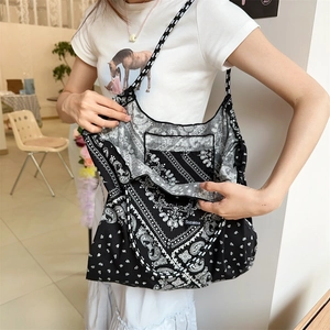 Close-up of black and white paisley tote bag featuring inner zipper pocket and brand label