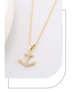 Close-up of a gold anchor pendant necklace featuring white cubic zirconia stone setting