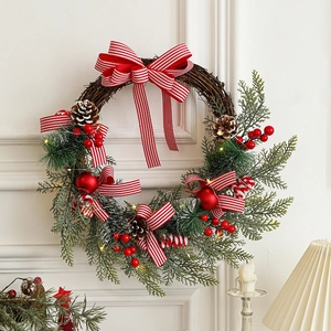 Christmas wreath with LED lights, pine cones, red berries and striped bow on white wall