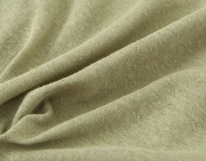 Close-up detail of soft linen blend fabric in light sage green with knit texture