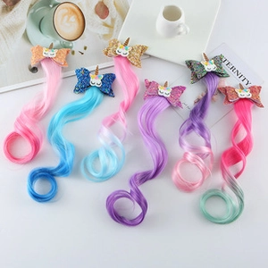 Flat lay of colorful unicorn hair clips with glitter bows and curly wig extensions