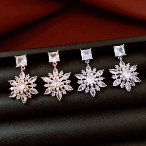 Macro detail of snowflake earrings with clear cubic zirconia in gold and silver plating