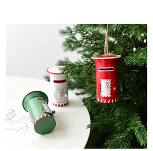 Close-up of three colorful mini Christmas mailbox ornaments hanging on a festive tree branch