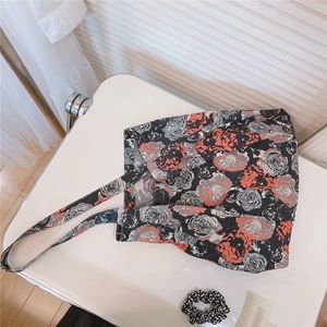 Detailed close-up of a vintage floral cotton tote bag with orange rose patterns on a white desk