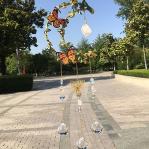 Detail of moon-shaped garden wind chime with green leaves, butterflies and crystal balls