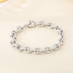 Polished stainless steel round link chain bracelet with lobster clasp on beige background