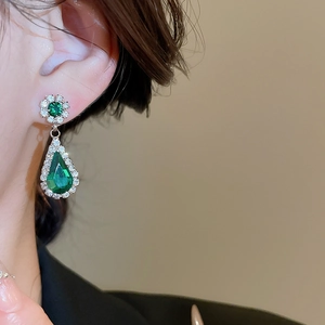 Detailed close-up of vintage flower and teardrop earrings with green gemstones and diamonds