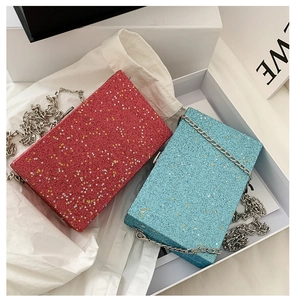 Close-up of glitter and star sequin finish on red and blue clutch bags with silver chain