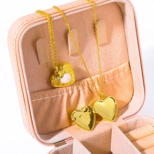 Golden heart locket necklace with pink opal pendant inside a pink velvet jewelry box