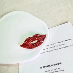 Chic red rhinestone lip brooch with sparkling crystals on a golden base in a flat lay setup