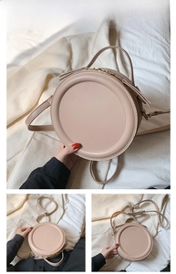 Detailansicht der khakifarbenen runden Handtasche mit Lederstruktur und langen Quasten
