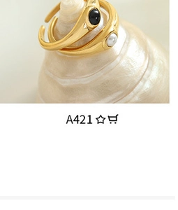 Macro shot of gold signet rings set with black gemstone and white pearl on shell