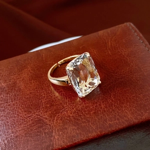 Macro shot of rectangular clear gemstone ring on luxury brown leather surface