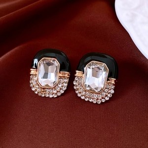 Macro view of vintage gold stud earrings with black enamel and sparkling rhinestones