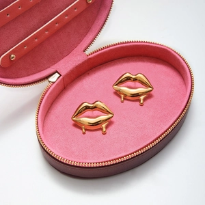 Boucles d'oreilles lèvres dorées effet fondant dans un écrin en velours rose poudré