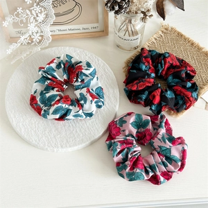 Detailed flat lay of three rose print fabric scrunchies in white, black and pink colors