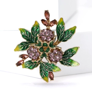Macro shot of gold-plated rose bud brooch with purple rhinestones and enamel leaves