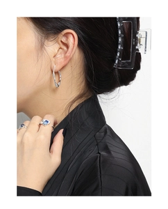 Detail shot of irregular silver earrings and blue stone rings on a model with black top