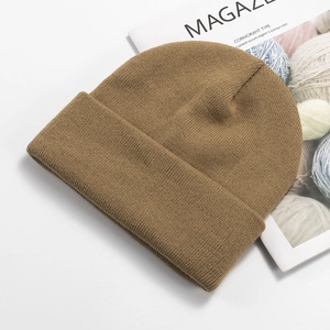 Detailed view of a camel knitted beanie with wide cuff on a minimalist magazine prop