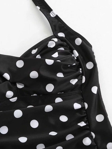 Detailed close-up of black and white polka dot swimsuit fabric with ruched design details