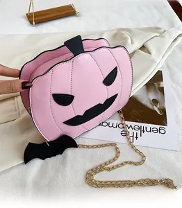 Detailed view of pink leather pumpkin bag with bat wings and gold chain on fabric