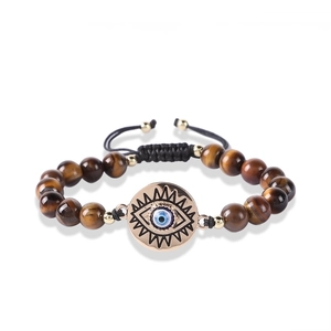 Macro view of natural tiger eye beads and evil eye pendant on adjustable woven bracelet