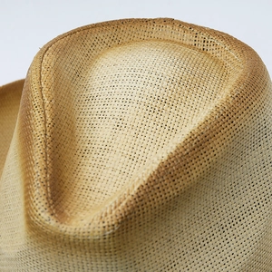 Top view of natural woven straw cowboy hat with classic indented crown and flat weave texture