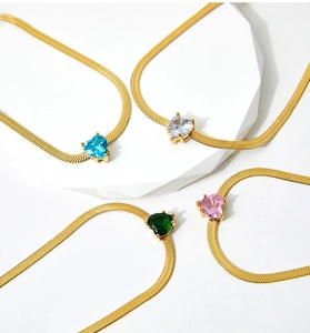 Detail of gold flat snake chain necklaces with heart-shaped emerald and pink zircon pendants