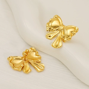 Detailed close-up of 18k gold plated bow stud earrings with embossed heart details