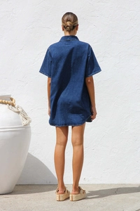 Rear view of a loose dark indigo denim shirt dress with short sleeves and a lapel collar