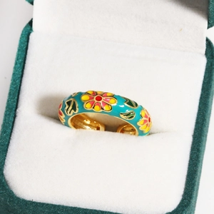 Close-up of enamel flower ring in green box with blue, pink and yellow floral details