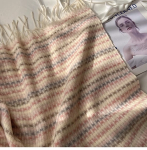 Close-up of pink and grey checkered knit scarf texture with soft fringed edges on satin