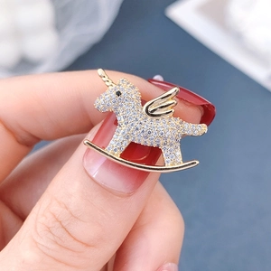 Detail of a gold unicorn rocking horse brooch with white crystals and black stone eye