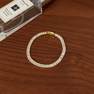 Detail of gold-plated tennis bracelet featuring baguette-cut zircon stones and clasp