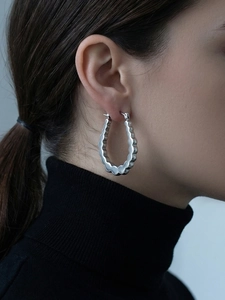 Silver wavy edge oval hoop earrings shown on model with mirror polished finish