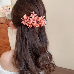 Close-up of peach fabric flower hair clip worn for a sweet and elegant hairstyle