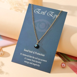 Close-up of golden evil eye charm necklace with blue bead on elegant display card